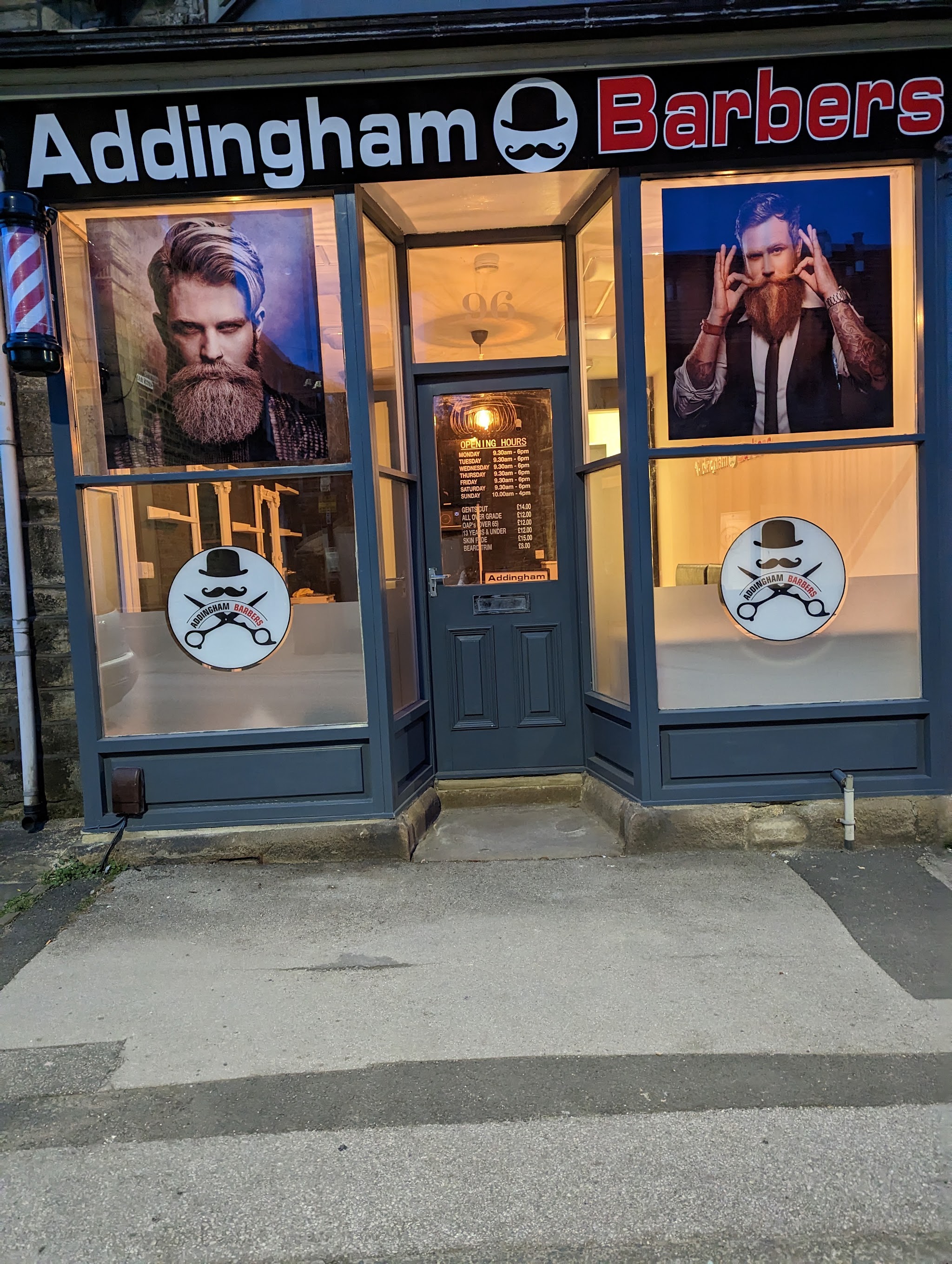 A warm light through the Addingham Barbers windows as evening arrives on Main Street